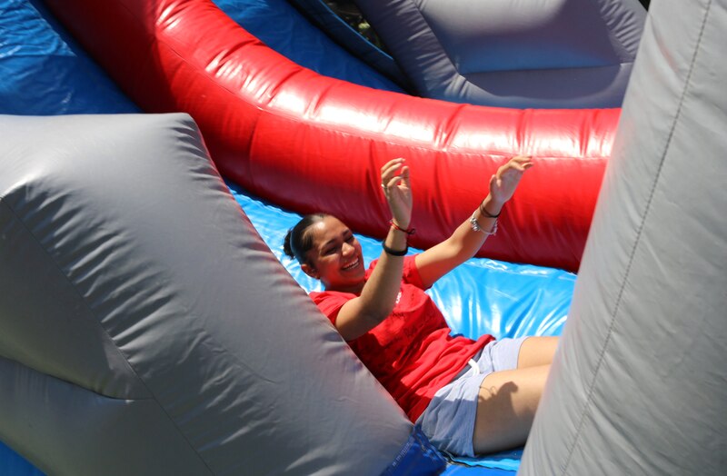 A girl in red plays on an outdoor inflatable.