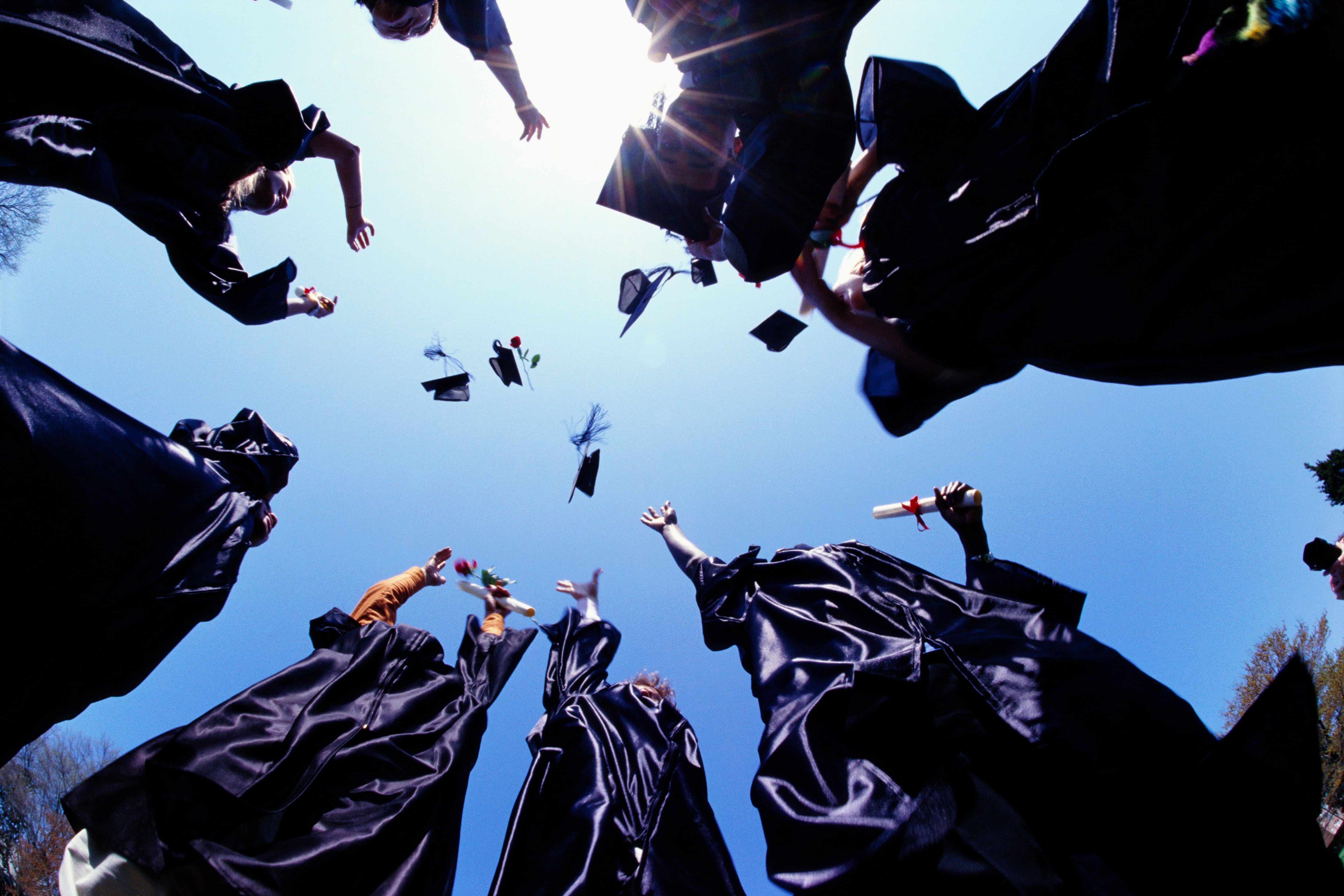 A bunch of people in purple graduation gowns toss their mortarboards.