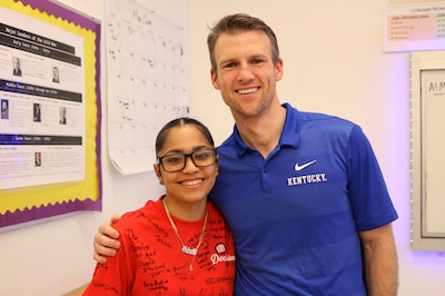 A student in a red shirt posing with a man in a blue shirt.