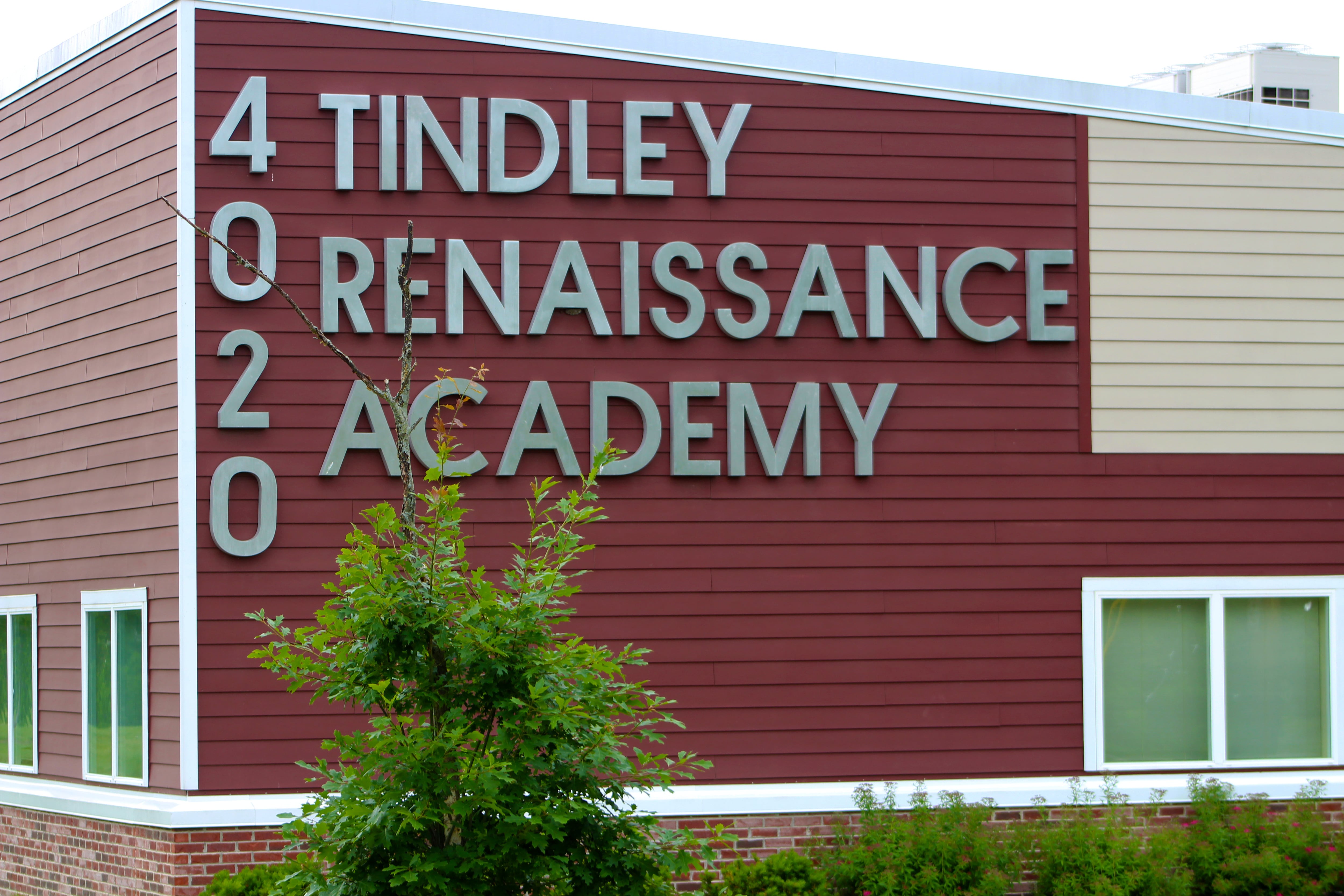 One corner of a red and white school building with the address and name of the school in large white letters.