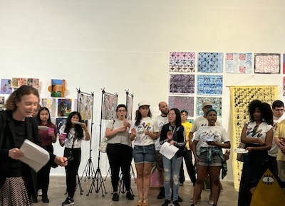 A group of people stand in front of a wall of art.