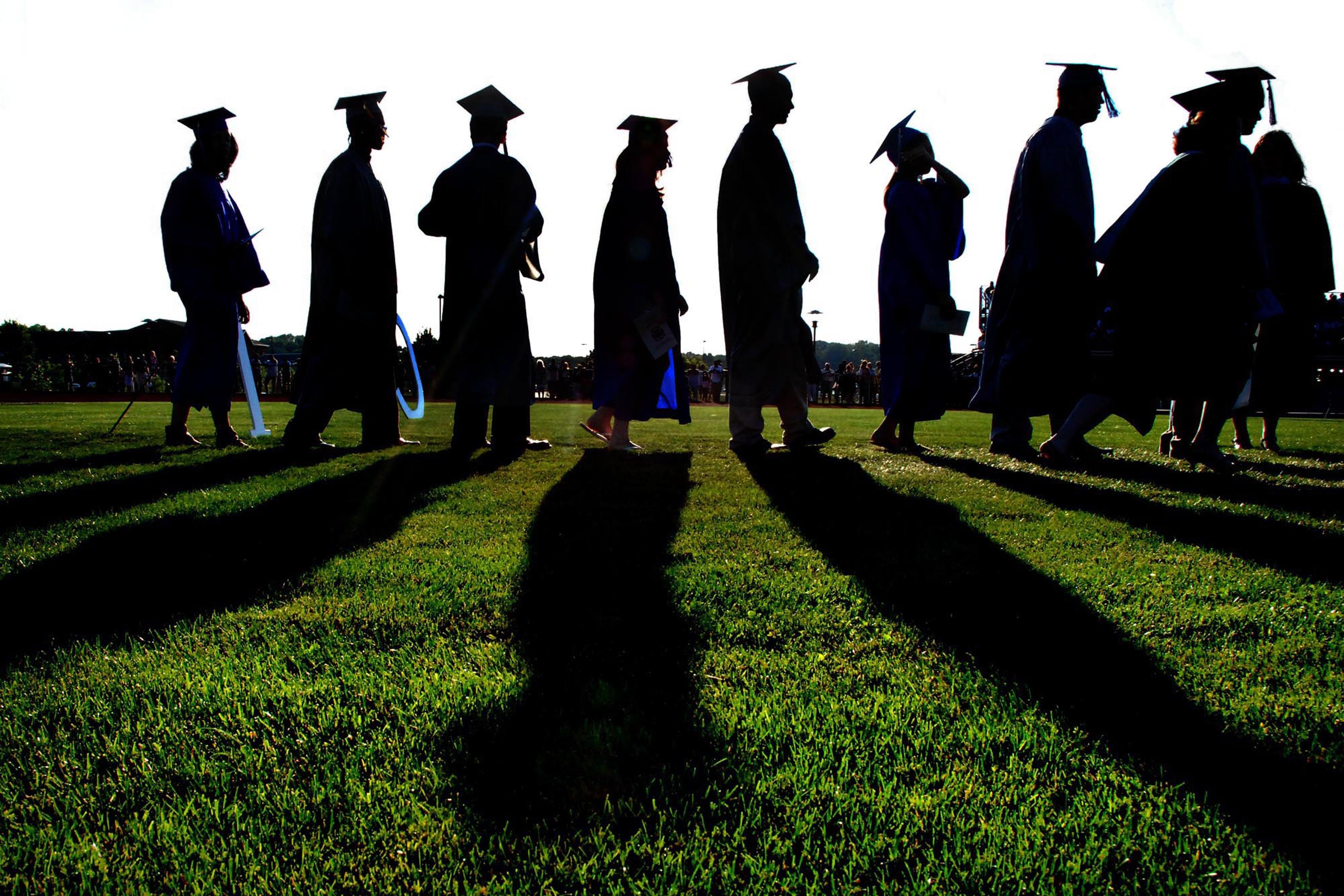 Graduates are silhouetted in a line.
